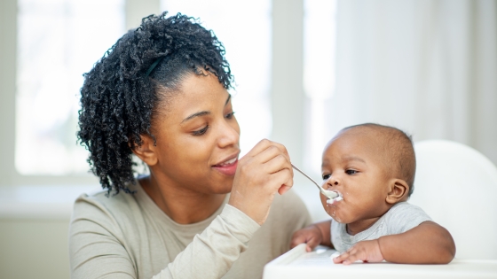 A baby boy in his highchair as his Mother feeds him A baby boy in his highchair as his Mother feeds him